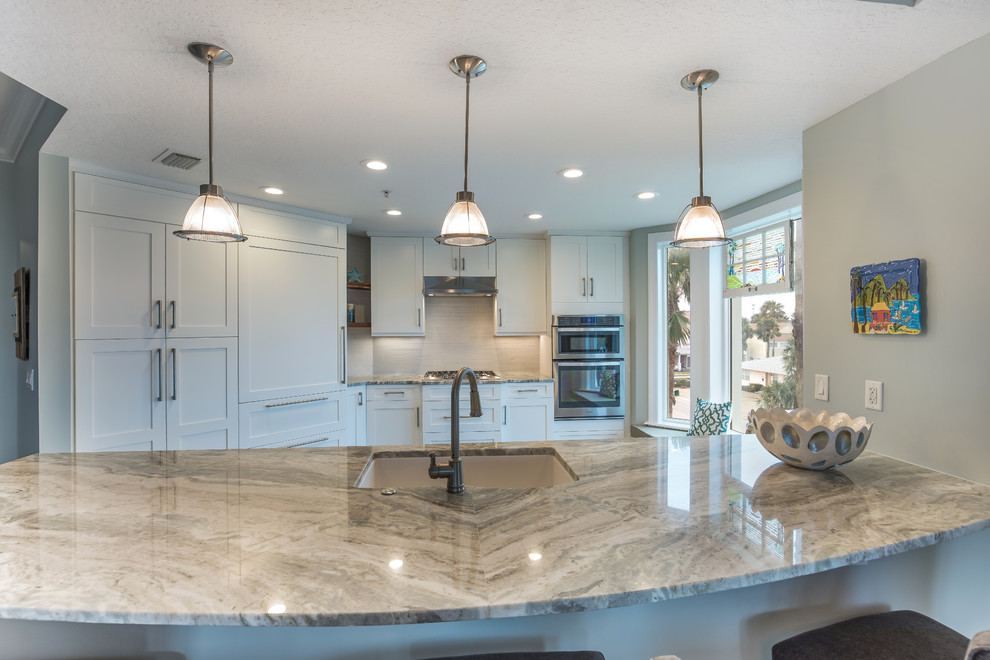 Design ideas for a beach style kitchen in Jacksonville with an undermount sink, shaker cabinets, white cabinets, granite benchtops, white splashback, limestone splashback, stainless steel appliances, ceramic floors, with island, grey floor and brown benchtop.