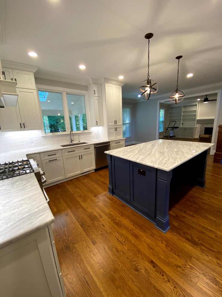 Design ideas for a large transitional u-shaped eat-in kitchen in Raleigh with an undermount sink, flat-panel cabinets, white cabinets, marble benchtops, white splashback, porcelain splashback, stainless steel appliances, medium hardwood floors, with island, brown floor and white benchtop.