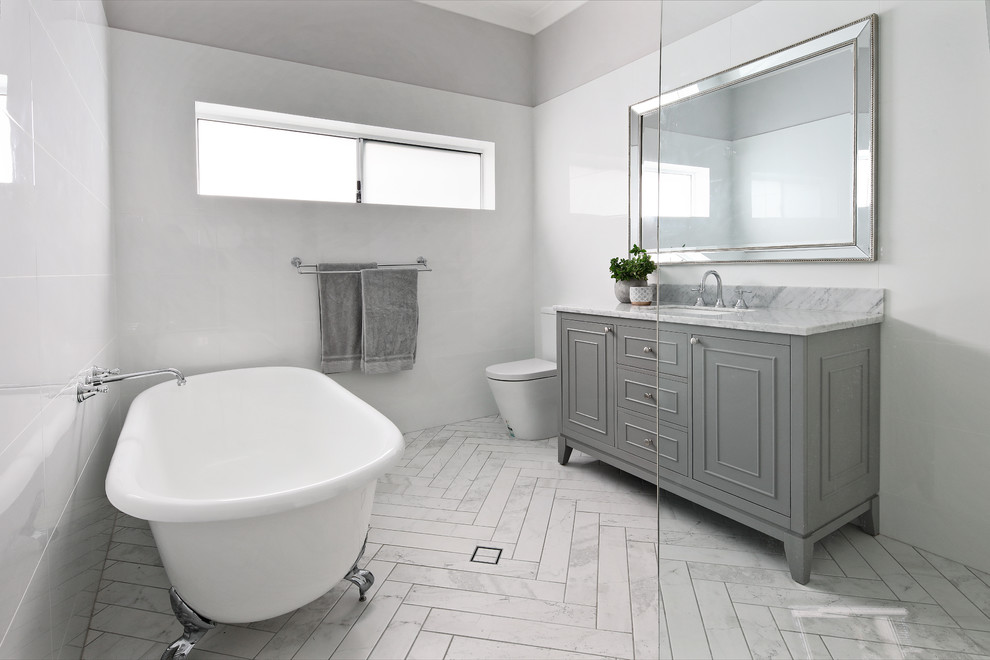 This is an example of a transitional master bathroom in Perth with recessed-panel cabinets, grey cabinets, a claw-foot tub, a curbless shower, white tile, white walls, an undermount sink, grey floor, an open shower and grey benchtops.