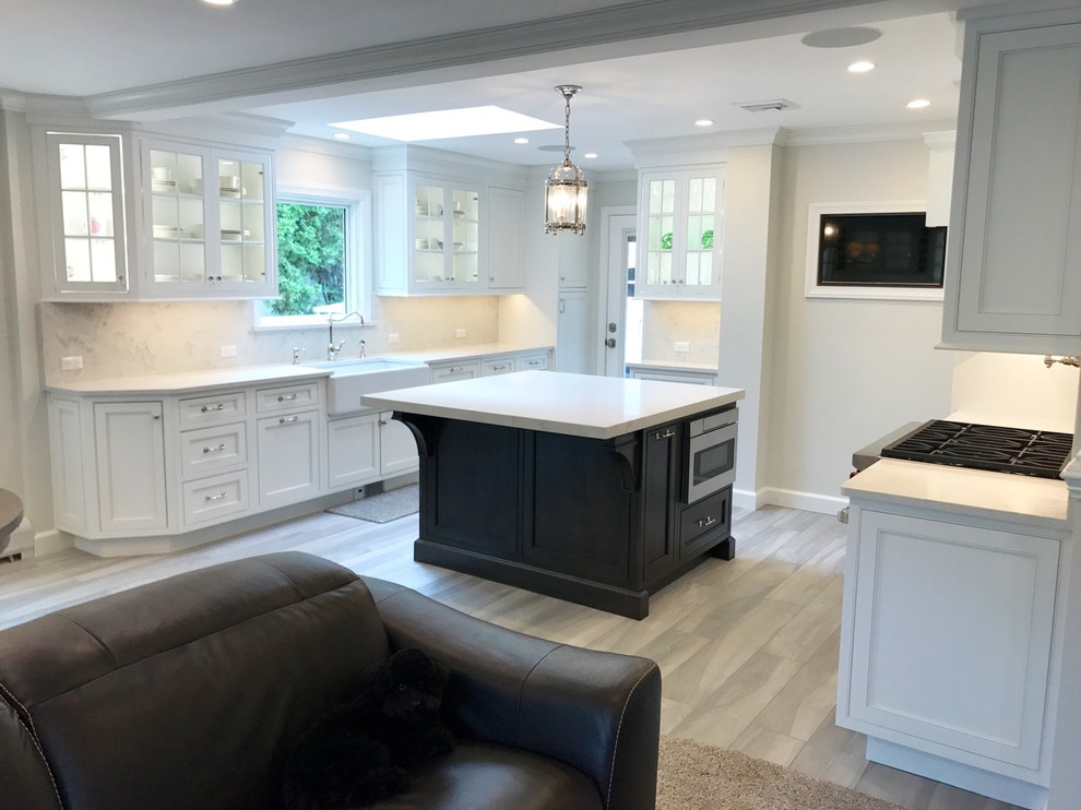 Open concept kitchen - mid-sized transitional u-shaped light wood floor and brown floor open concept kitchen idea with a farmhouse sink, recessed-panel cabinets, white cabinets, marble countertops, white backsplash, marble backsplash, stainless steel appliances and an island