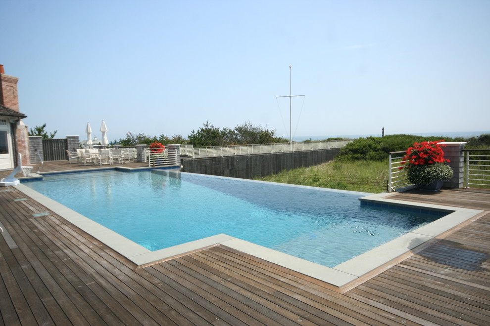 This is an example of a contemporary rectangular infinity pool in New York with decking.