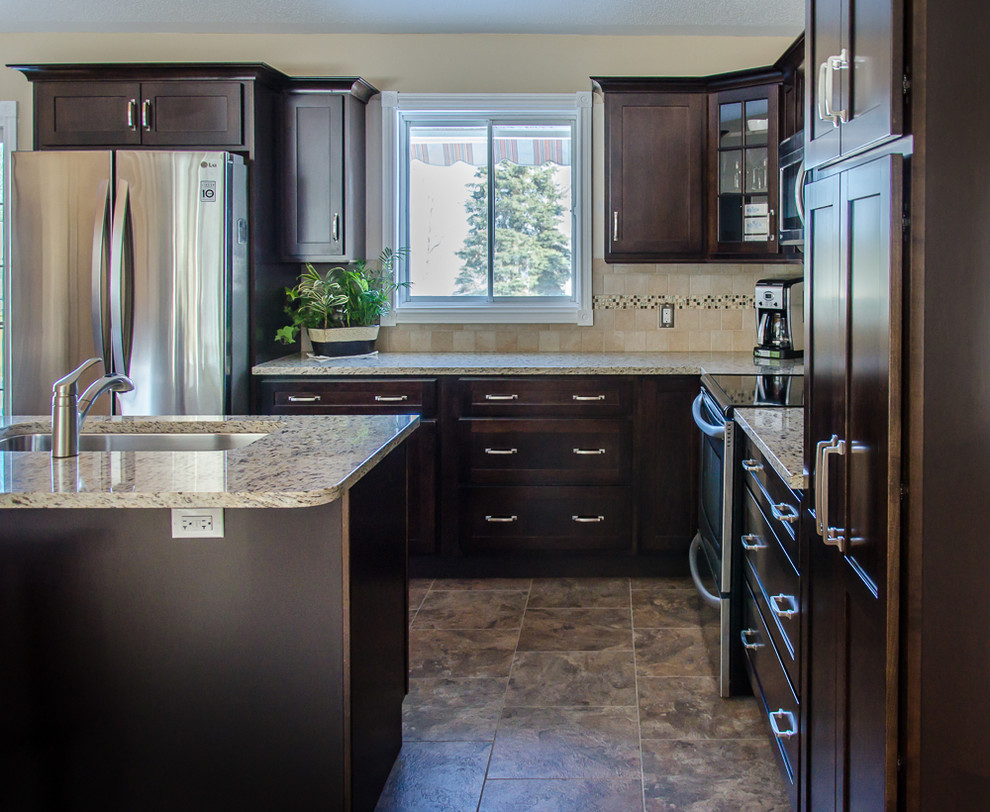 Photo of a mid-sized transitional l-shaped open plan kitchen in Toronto with an undermount sink, shaker cabinets, dark wood cabinets, granite benchtops, beige splashback, ceramic splashback, stainless steel appliances, porcelain floors, with island and brown floor.