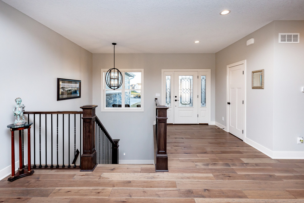 Inspiration for a mid-sized transitional medium tone wood floor and brown floor foyer remodel with gray walls and a white front door