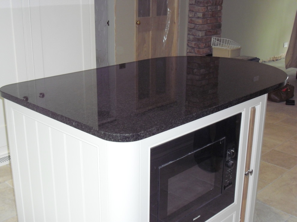 Photo of a mid-sized traditional l-shaped eat-in kitchen in Manchester with an undermount sink, shaker cabinets, white cabinets, granite benchtops, black splashback, black appliances, ceramic floors and with island.