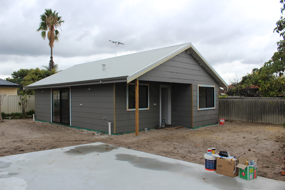 Mid-sized industrial one-storey grey house exterior in Perth with wood siding, a gable roof and a metal roof.