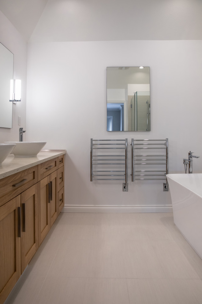 This is an example of a large traditional master bathroom in Vancouver with shaker cabinets, medium wood cabinets, a freestanding tub, a corner shower, a two-piece toilet, gray tile, porcelain tile, grey walls, porcelain floors, a vessel sink, engineered quartz benchtops, grey floor, a sliding shower screen, white benchtops, a niche, a double vanity and a built-in vanity.