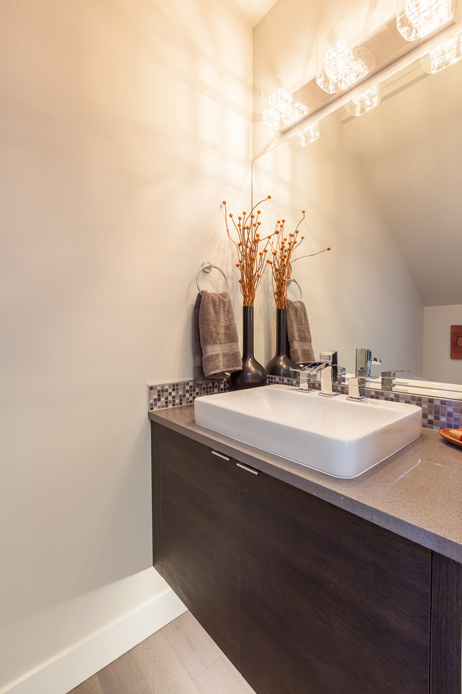 Small modern powder room in Seattle with flat-panel cabinets, dark wood cabinets, a one-piece toilet, gray tile, mosaic tile, white walls, vinyl floors, a vessel sink, terrazzo benchtops and grey benchtops.