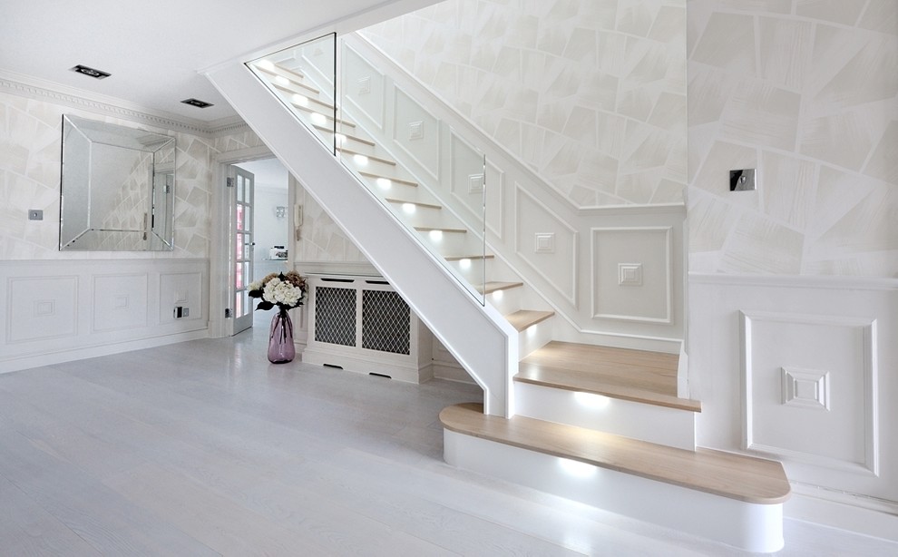 Photo of a large contemporary wood curved staircase in London with glass railing and painted wood risers.