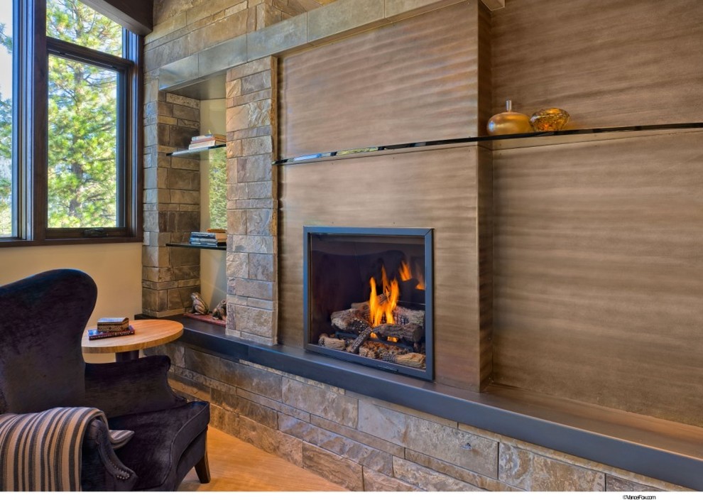 This is an example of a mid-sized contemporary open concept living room in Denver with brown walls, light hardwood floors, a standard fireplace, a wood fireplace surround and no tv.