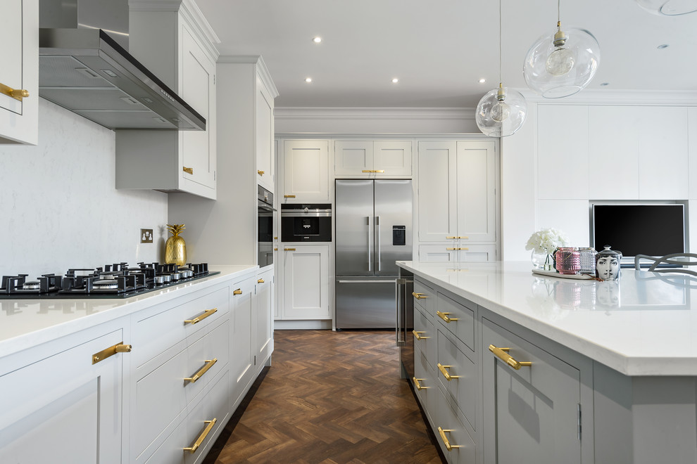 Inspiration for a mid-sized transitional u-shaped open plan kitchen in London with an integrated sink, shaker cabinets, grey cabinets, quartzite benchtops, white splashback, stainless steel appliances, laminate floors, with island, brown floor and stone slab splashback.