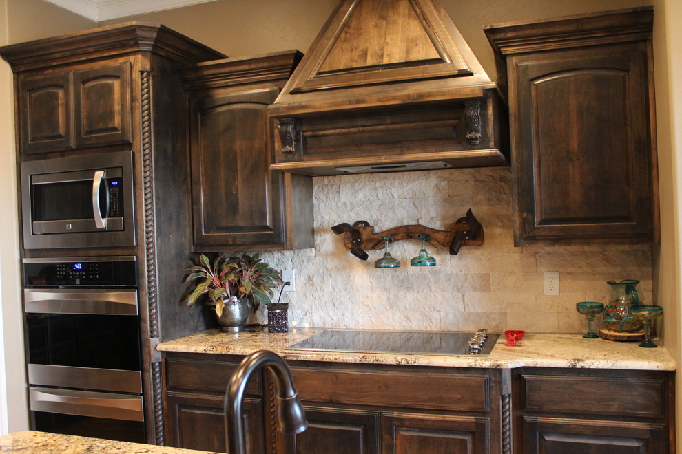 Inspiration for a mid-sized rustic ceramic tile eat-in kitchen remodel in Austin with a drop-in sink, raised-panel cabinets, dark wood cabinets, granite countertops, beige backsplash, stone tile backsplash, stainless steel appliances and an island