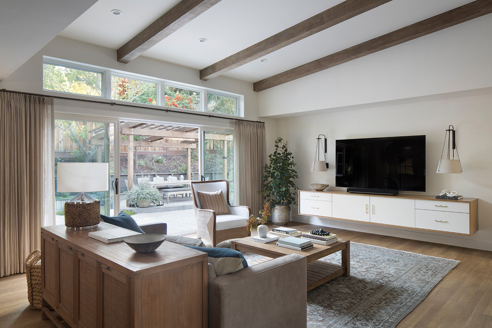 This is an example of a mid-sized transitional open concept living room in San Francisco with white walls, no fireplace, a wall-mounted tv, brown floor and medium hardwood floors.
