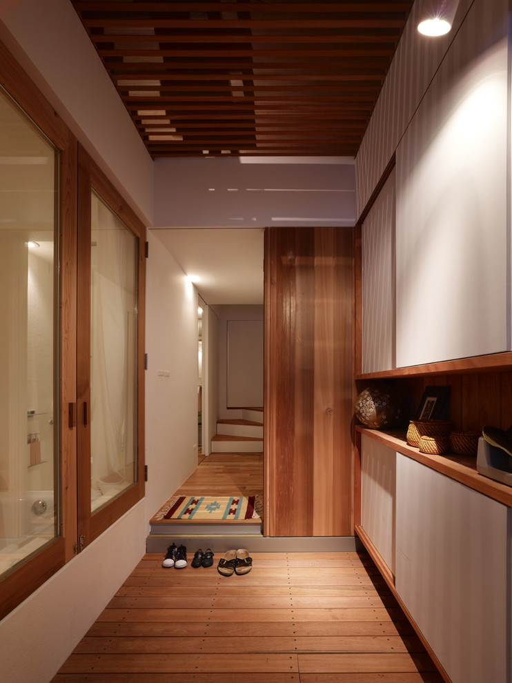 Photo of a contemporary entryway in Kobe with white walls, medium hardwood floors and brown floor.