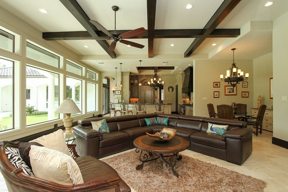 Photo of a large mediterranean open concept family room in Houston with beige walls, travertine floors, a corner fireplace, a brick fireplace surround and a wall-mounted tv.