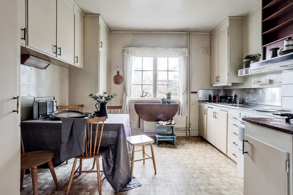 This is an example of a mid-sized country l-shaped kitchen in Gothenburg with flat-panel cabinets, beige cabinets, no island and linoleum floors.