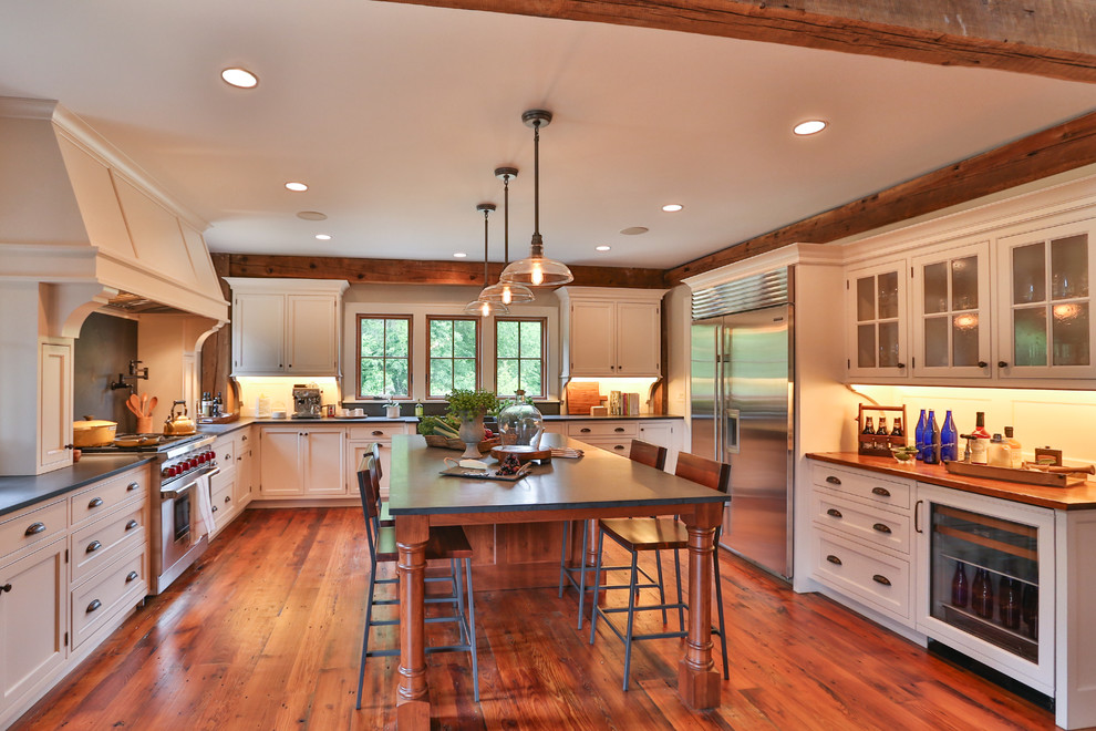Country u-shaped kitchen in Other with a farmhouse sink, beaded inset cabinets, white cabinets, stainless steel appliances, dark hardwood floors, with island, brown floor and grey benchtop.