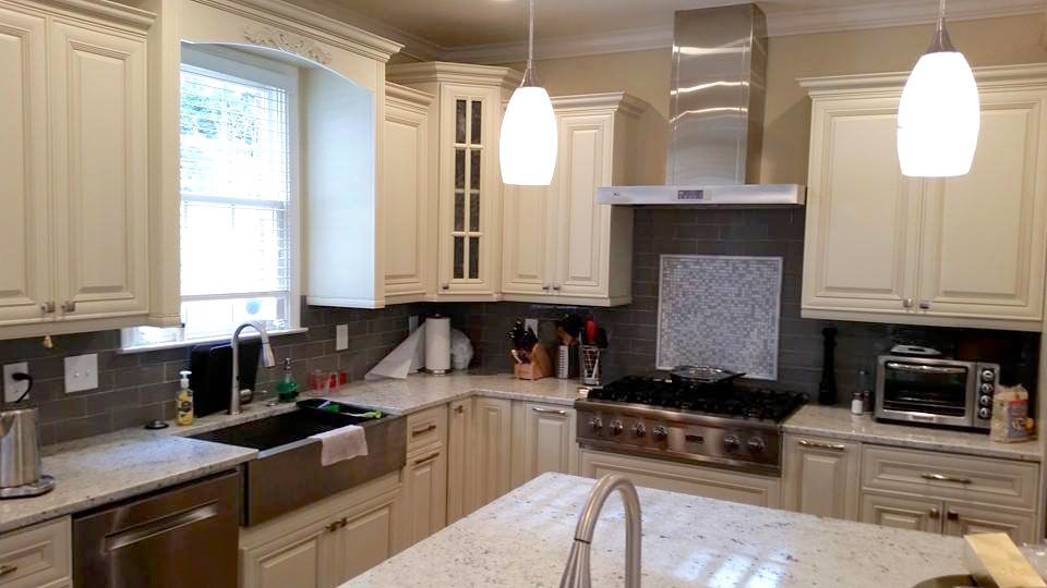 Example of a large transitional l-shaped dark wood floor and brown floor eat-in kitchen design in Miami with a farmhouse sink, raised-panel cabinets, white cabinets, gray backsplash, subway tile backsplash, stainless steel appliances and an island