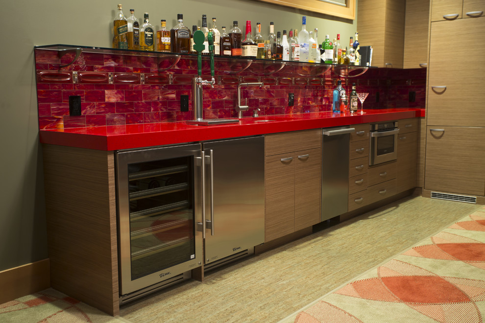This is an example of a large transitional single-wall home bar in Seattle with an undermount sink, flat-panel cabinets, medium wood cabinets, quartz benchtops, red splashback, glass tile splashback and cork floors.