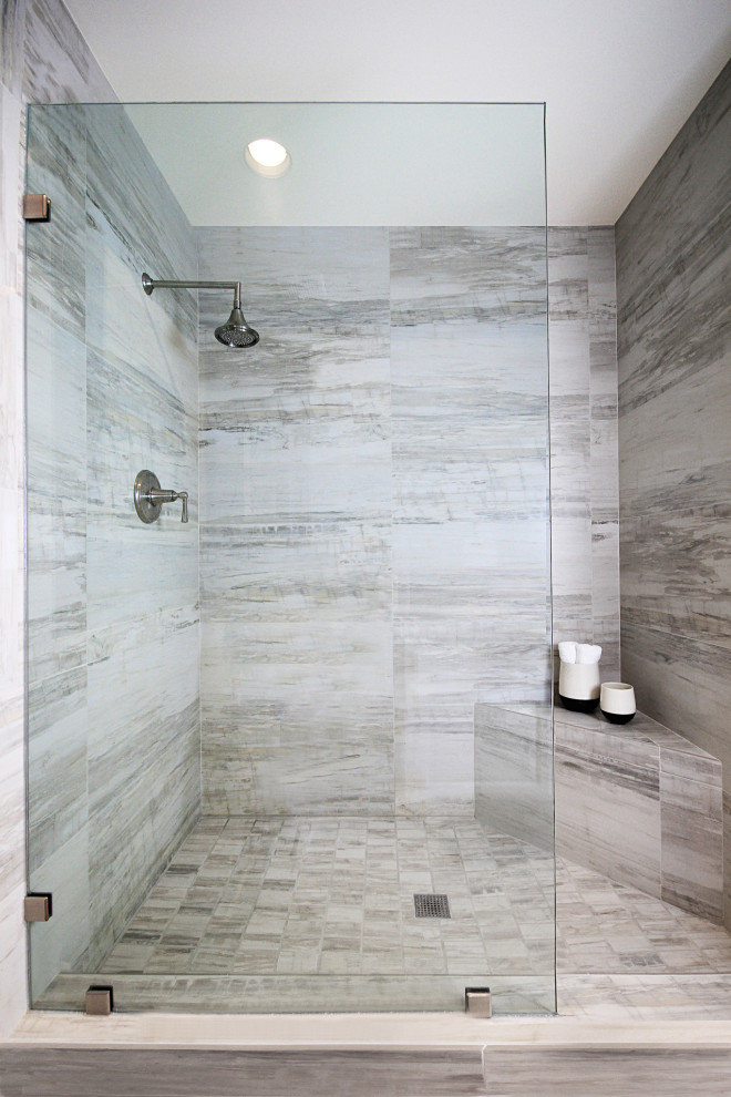 This is an example of a modern bathroom with white cabinets, an open shower, a one-piece toilet, black walls, marble floors, a drop-in sink, tile benchtops, white floor, an open shower, white benchtops and a double vanity.