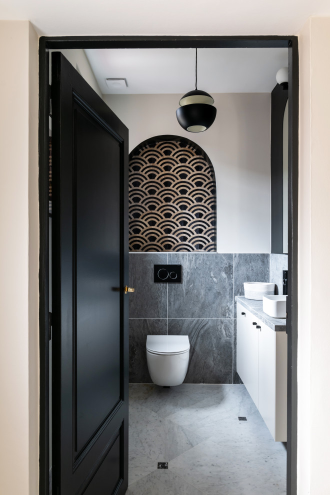 Design ideas for a large contemporary cloakroom in Paris with beaded cabinets, beige cabinets, a wall mounted toilet, grey tiles, ceramic tiles, beige walls, marble flooring, a built-in sink, tiled worktops, white floors, grey worktops, a floating vanity unit and wallpapered walls.