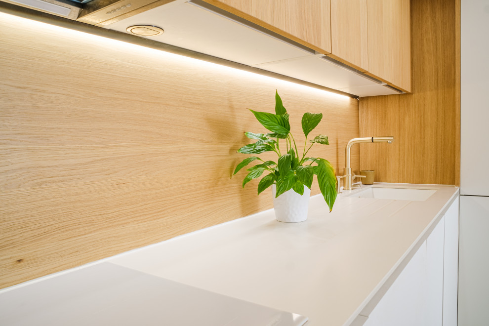 Esempio di una cucina moderna di medie dimensioni con pavimento in legno massello medio, lavello integrato, ante a filo, ante bianche, paraspruzzi in legno, elettrodomestici bianchi, pavimento bianco e top bianco