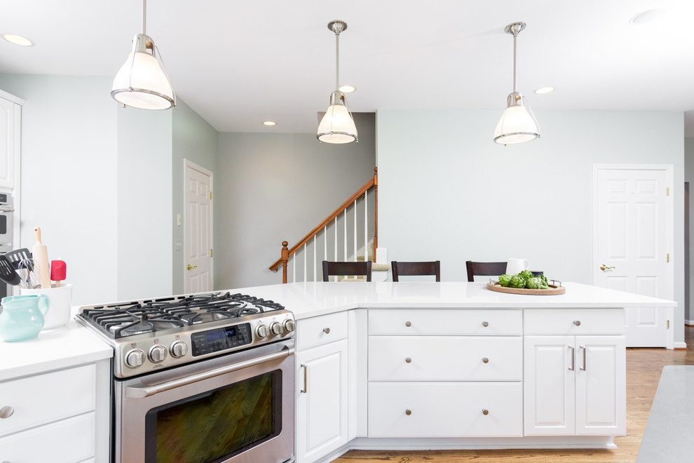 Eat-in kitchen - large transitional u-shaped medium tone wood floor and brown floor eat-in kitchen idea in Detroit with an undermount sink, raised-panel cabinets, white cabinets, quartz countertops, white backsplash, ceramic backsplash, an island and white appliances