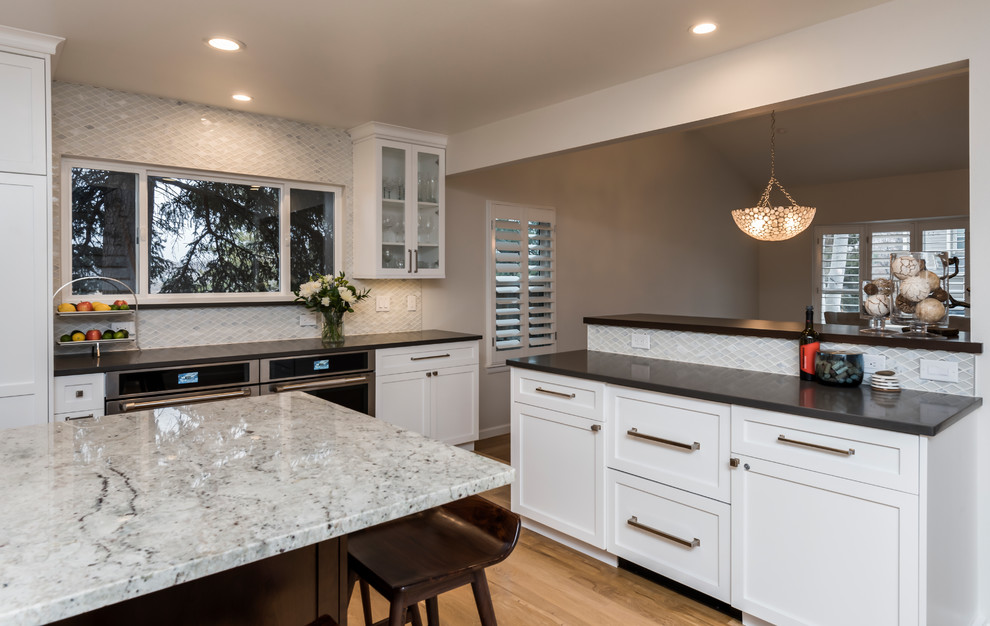 Example of a large transitional light wood floor eat-in kitchen design in Denver with a single-bowl sink, shaker cabinets, white cabinets, quartz countertops, white backsplash, marble backsplash, stainless steel appliances, two islands and gray countertops