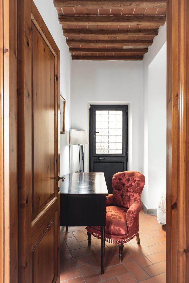 Ispirazione per una piccola camera matrimoniale minimalista con pareti bianche, pavimento in terracotta, pavimento rosso, travi a vista e abbinamento di mobili antichi e moderni