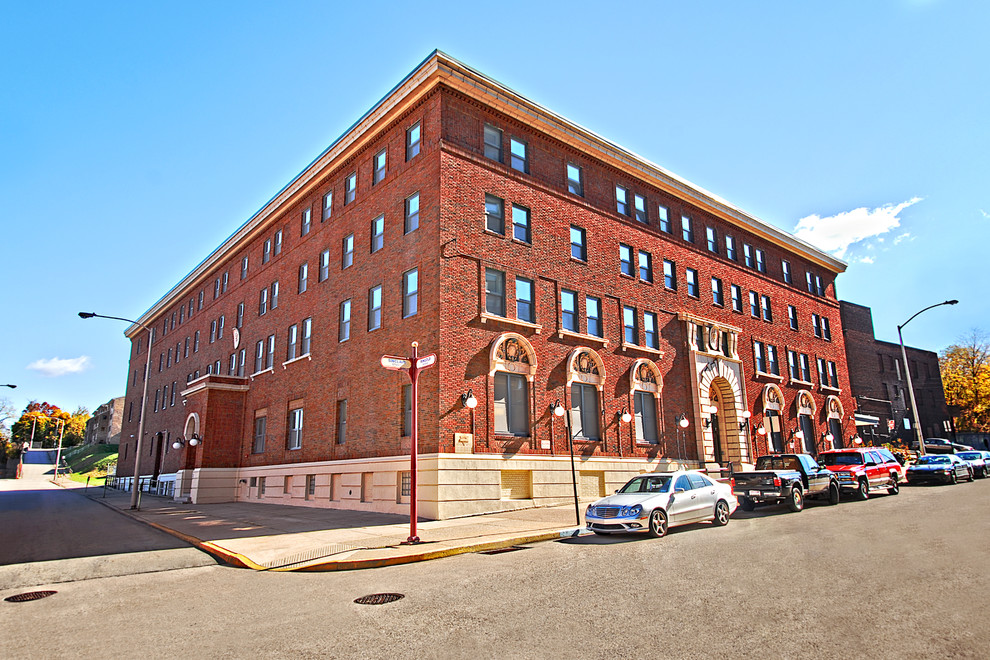 This is an example of an expansive industrial three-storey brick red apartment exterior in Denver with a flat roof.