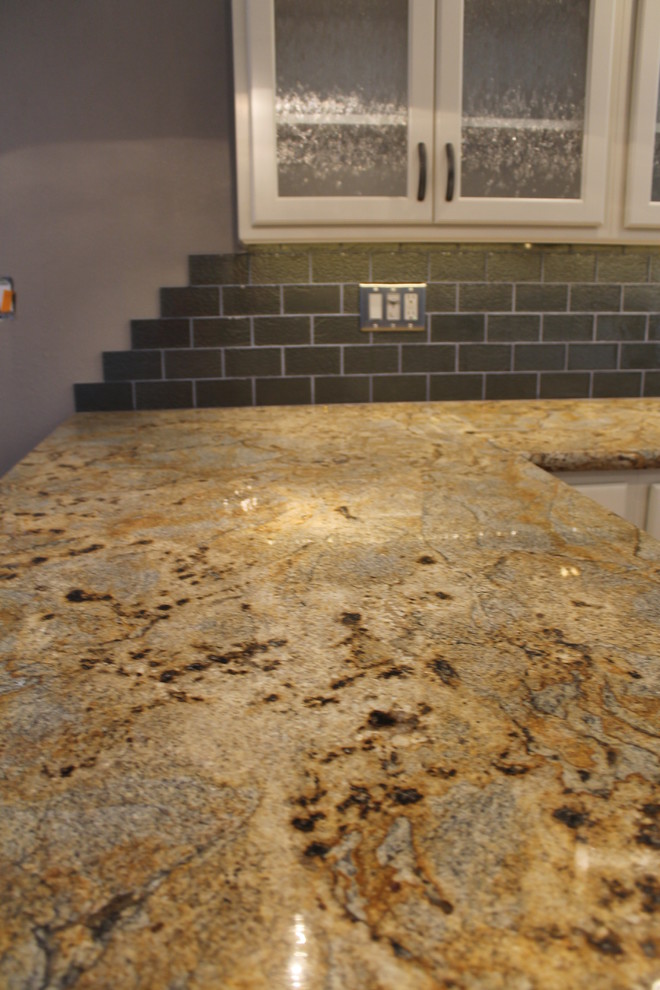 Example of a mid-sized transitional u-shaped dark wood floor and brown floor eat-in kitchen design in Phoenix with an undermount sink, raised-panel cabinets, white cabinets, granite countertops, green backsplash, glass tile backsplash, stainless steel appliances and a peninsula