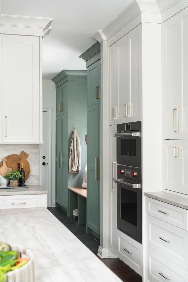 This is an example of a mid-sized transitional u-shaped utility room in Chicago with an undermount sink, shaker cabinets, green cabinets, quartz benchtops, white walls, porcelain floors, a stacked washer and dryer, black floor and white benchtop.
