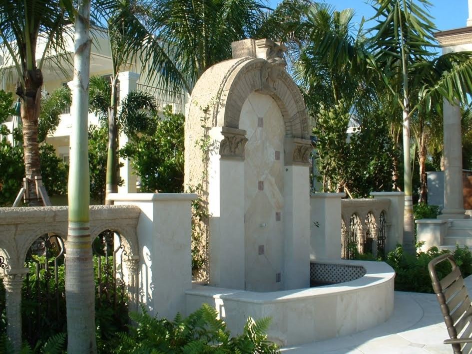 This is an example of a large mediterranean backyard patio in Miami with a water feature, concrete pavers and no cover.