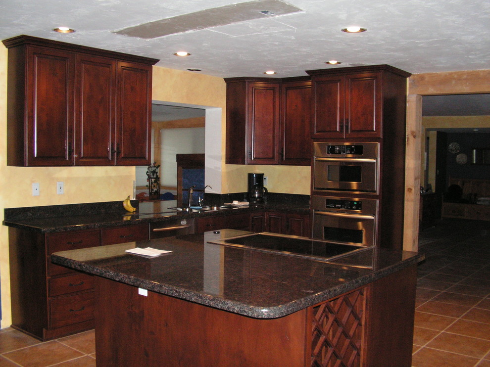 Example of a transitional kitchen design in Phoenix with raised-panel cabinets, dark wood cabinets, stainless steel appliances and an island