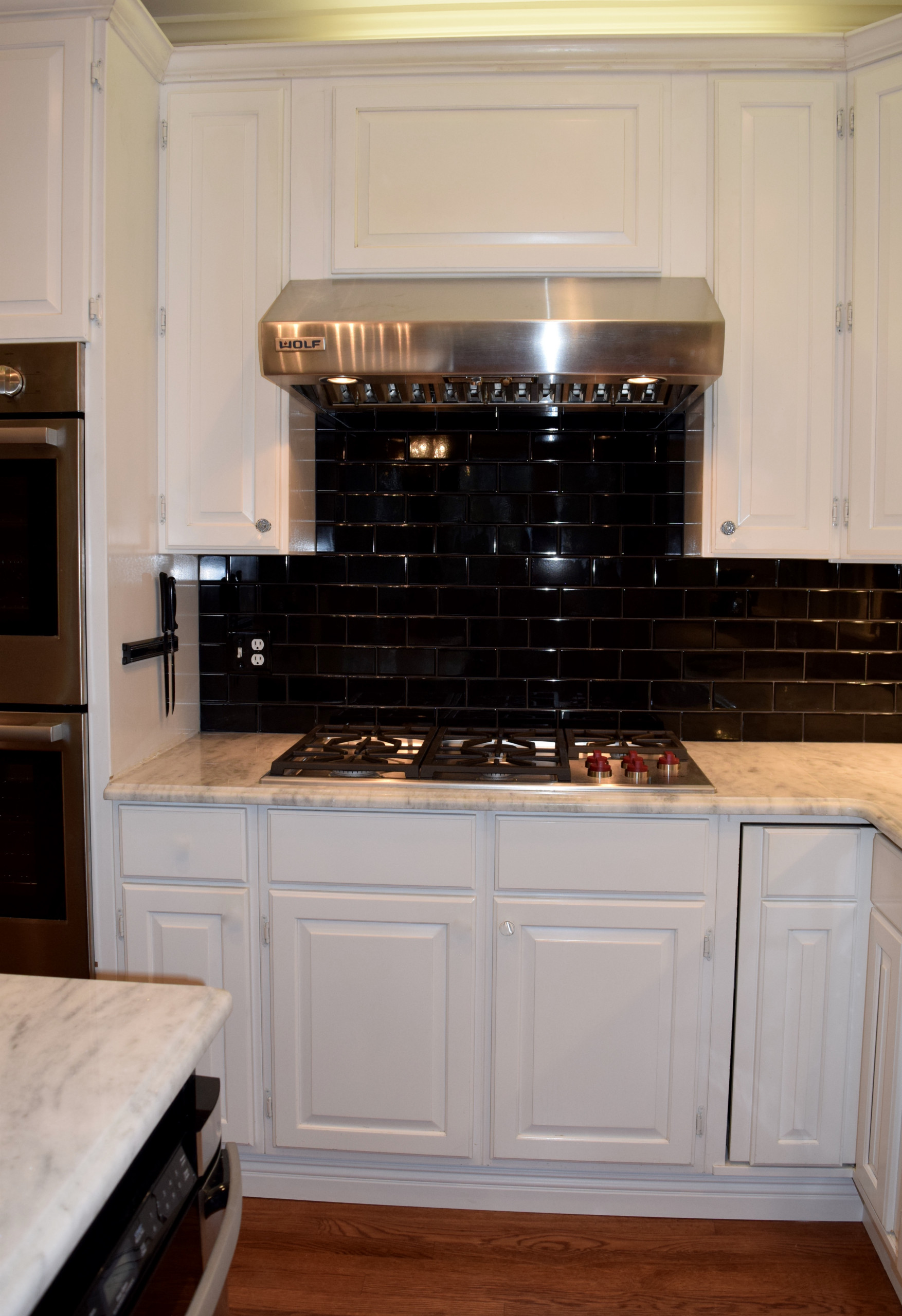 Stainless cooktop and hood with tile backsplash.