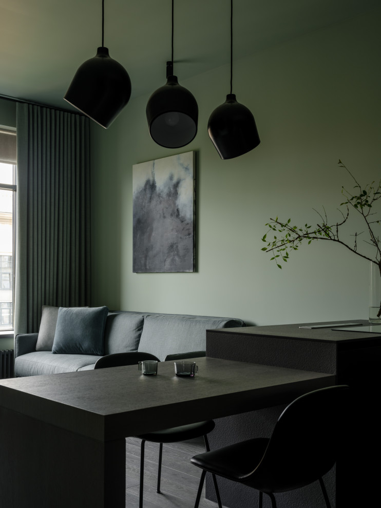 Пример оригинального дизайна: гостиная комната среднего размера в современном стиле с с книжными шкафами и полками, зелеными стенами, скрытым телевизором, зоной отдыха и серым полом