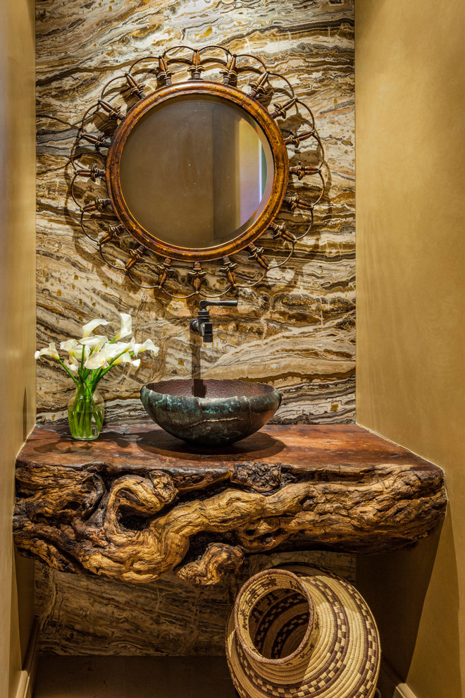 Photo of a mid-sized eclectic powder room in Phoenix with a two-piece toilet, orange walls, limestone floors, a vessel sink, wood benchtops and beige floor.