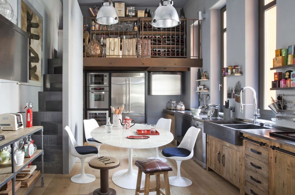 Design ideas for an eclectic l-shaped eat-in kitchen in Milan with a farmhouse sink, flat-panel cabinets, medium wood cabinets, stainless steel appliances, light hardwood floors, no island, beige floor and grey benchtop.