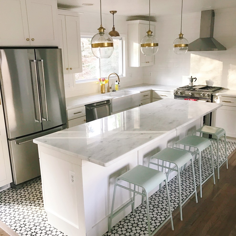 Large transitional medium tone wood floor and brown floor kitchen photo in Dallas with a farmhouse sink, shaker cabinets, white cabinets, quartzite countertops, multicolored backsplash, cement tile backsplash, stainless steel appliances and an island