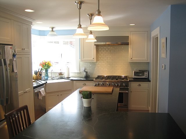 Kitchen - transitional medium tone wood floor kitchen idea in Boston with a farmhouse sink, white cabinets, white backsplash and stainless steel appliances