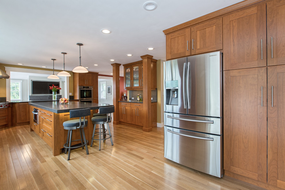 Example of a transitional u-shaped medium tone wood floor kitchen design in Boston with an undermount sink, shaker cabinets, medium tone wood cabinets, quartz countertops, gray backsplash, stone slab backsplash, stainless steel appliances and an island