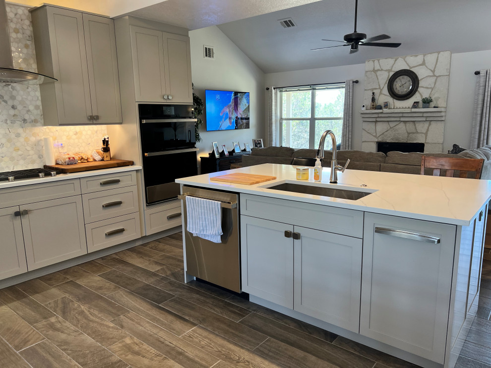 Inspiration for a large transitional u-shaped porcelain tile and brown floor eat-in kitchen remodel in Austin with an undermount sink, shaker cabinets, gray cabinets, quartz countertops, white backsplash, marble backsplash, stainless steel appliances, an island and white countertops