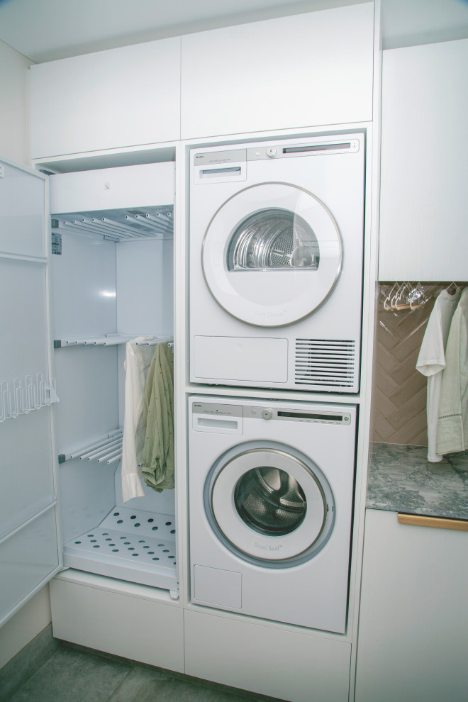 Exempel på en modern flerfärgade flerfärgat tvättstuga enbart för tvätt, med en dubbel diskho, vita skåp, marmorbänkskiva, rosa stänkskydd, stänkskydd i tunnelbanekakel, vita väggar, klinkergolv i porslin och en tvättpelare