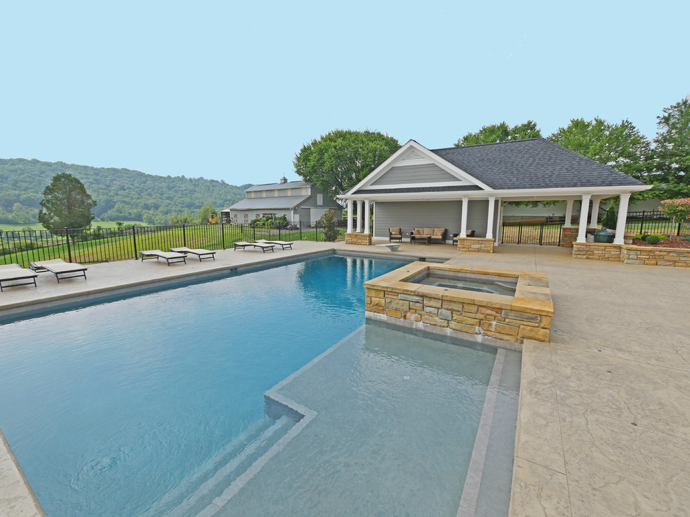Inspiration for a large transitional backyard rectangular natural pool in Other with a pool house and stamped concrete.
