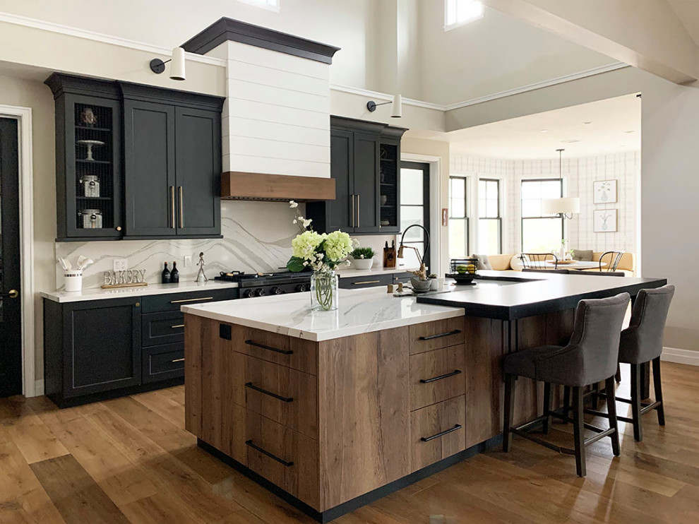 Design ideas for a large country l-shaped open plan kitchen in Santa Barbara with a farmhouse sink, quartz benchtops, engineered quartz splashback, black appliances, light hardwood floors, with island and exposed beam.