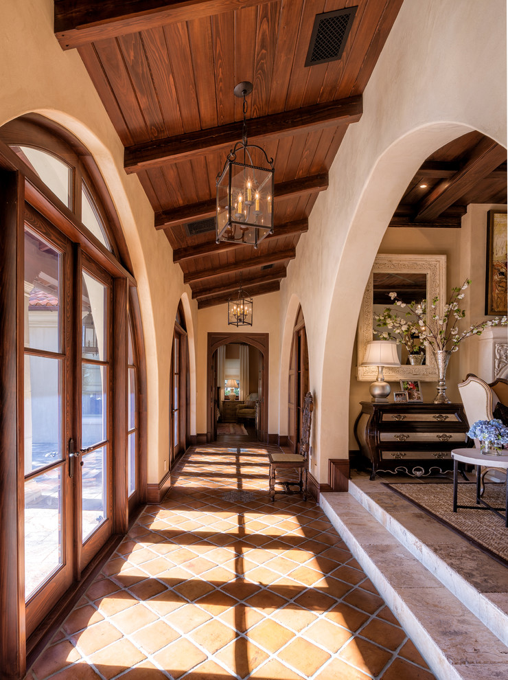 Inspiration for a mediterranean hallway in Tampa with beige walls and terra-cotta floors.