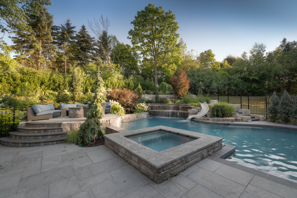 Inspiration för en stor vintage anpassad pool på baksidan av huset, med naturstensplattor