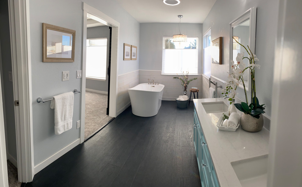 Photo of a large contemporary master bathroom in Other with shaker cabinets, turquoise cabinets, a freestanding tub, an alcove shower, a two-piece toilet, white tile, grey walls, vinyl floors, an undermount sink, quartzite benchtops, black floor, a sliding shower screen, white benchtops, an enclosed toilet, a double vanity, a freestanding vanity and wood walls.
