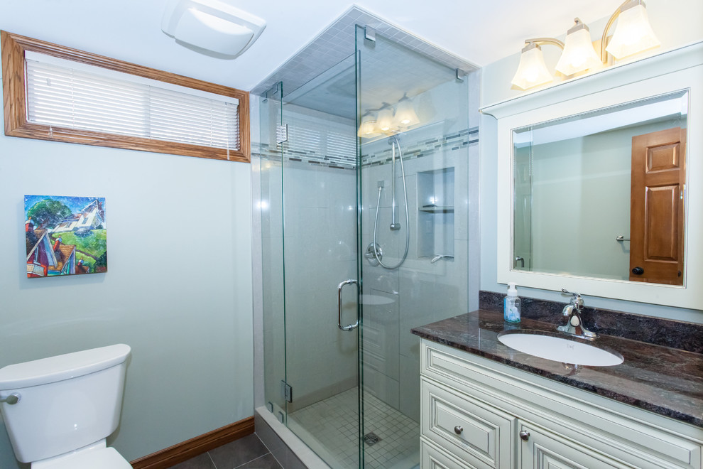 Inspiration for a small transitional 3/4 gray tile and porcelain tile porcelain tile and gray floor corner shower remodel with raised-panel cabinets, white cabinets, a two-piece toilet, green walls, an undermount sink, granite countertops and a hinged shower door