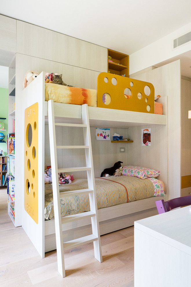 Design ideas for a contemporary gender-neutral kids' bedroom for kids 4-10 years old in Milan with white walls and light hardwood floors.