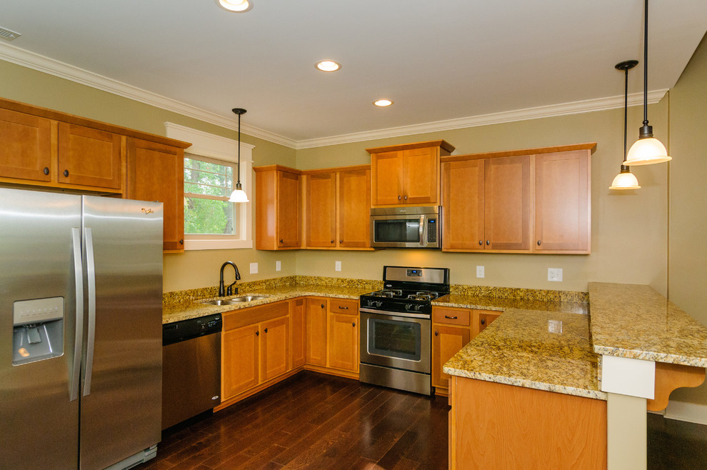 Large transitional u-shaped dark wood floor eat-in kitchen photo with a double-bowl sink, raised-panel cabinets, light wood cabinets, granite countertops, beige backsplash, stainless steel appliances and no island